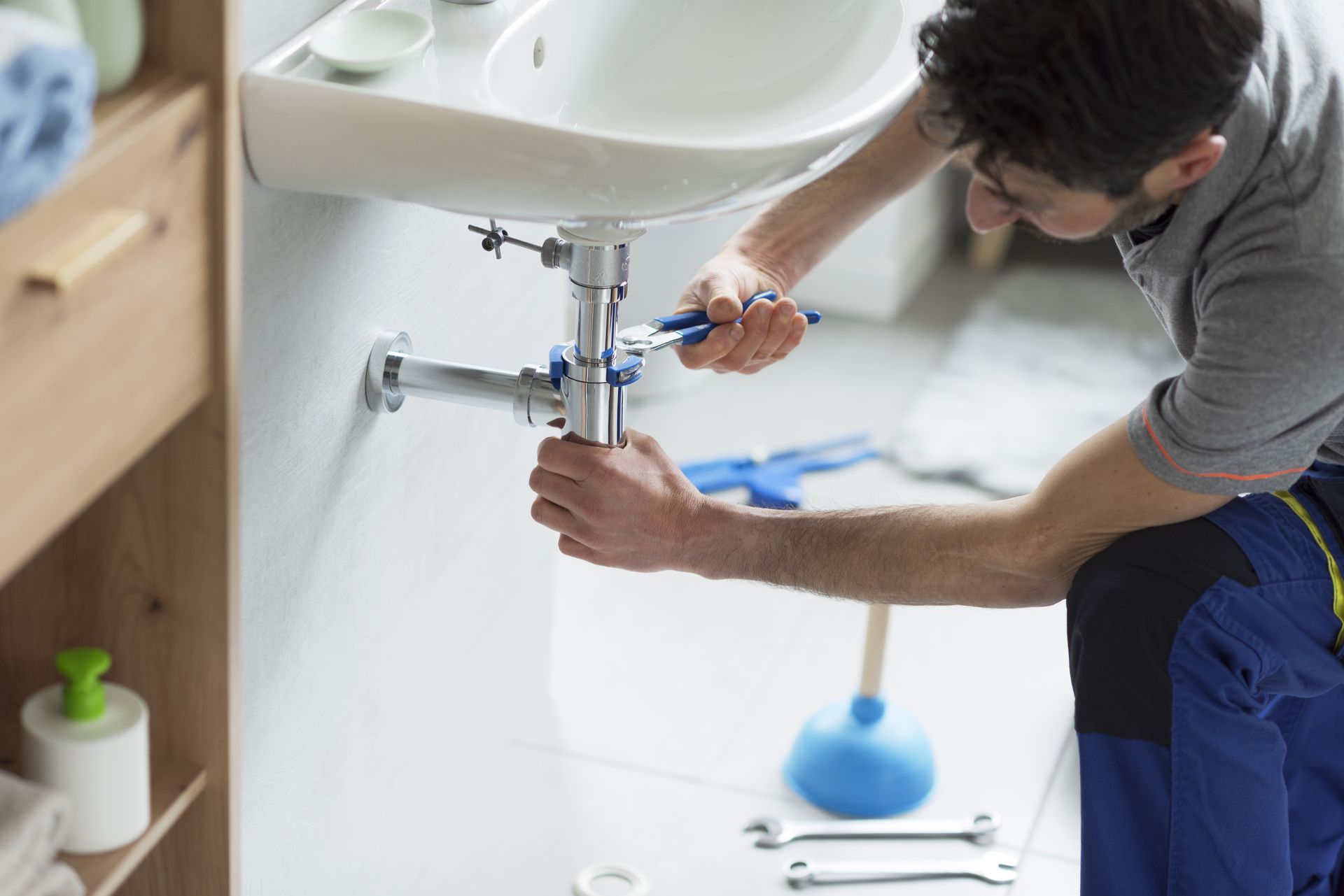 A plumber fixing a sink drain as part of residential plumbing services