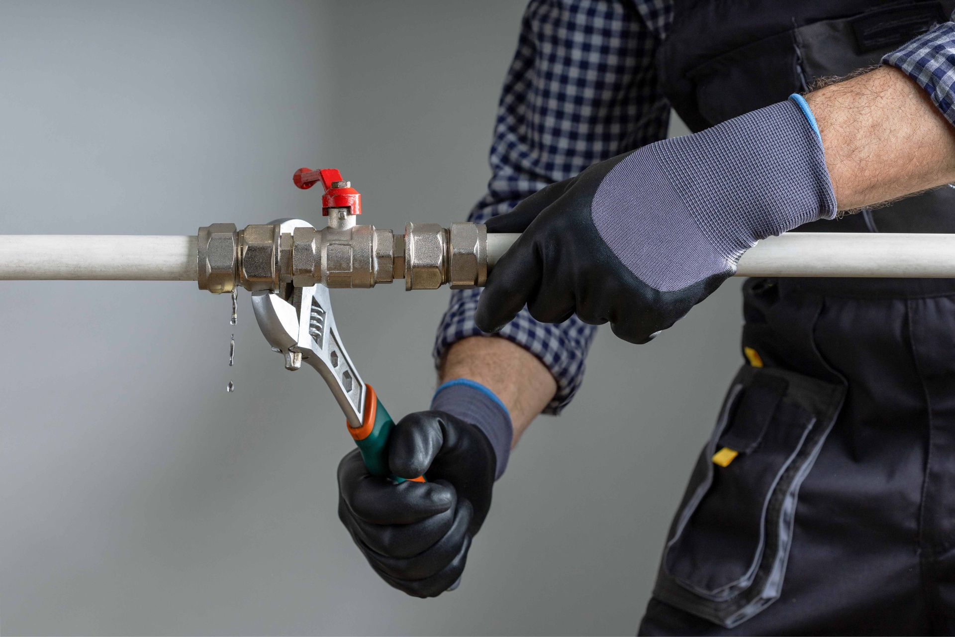 An adjustable wrench tightening a leaking metal pipe