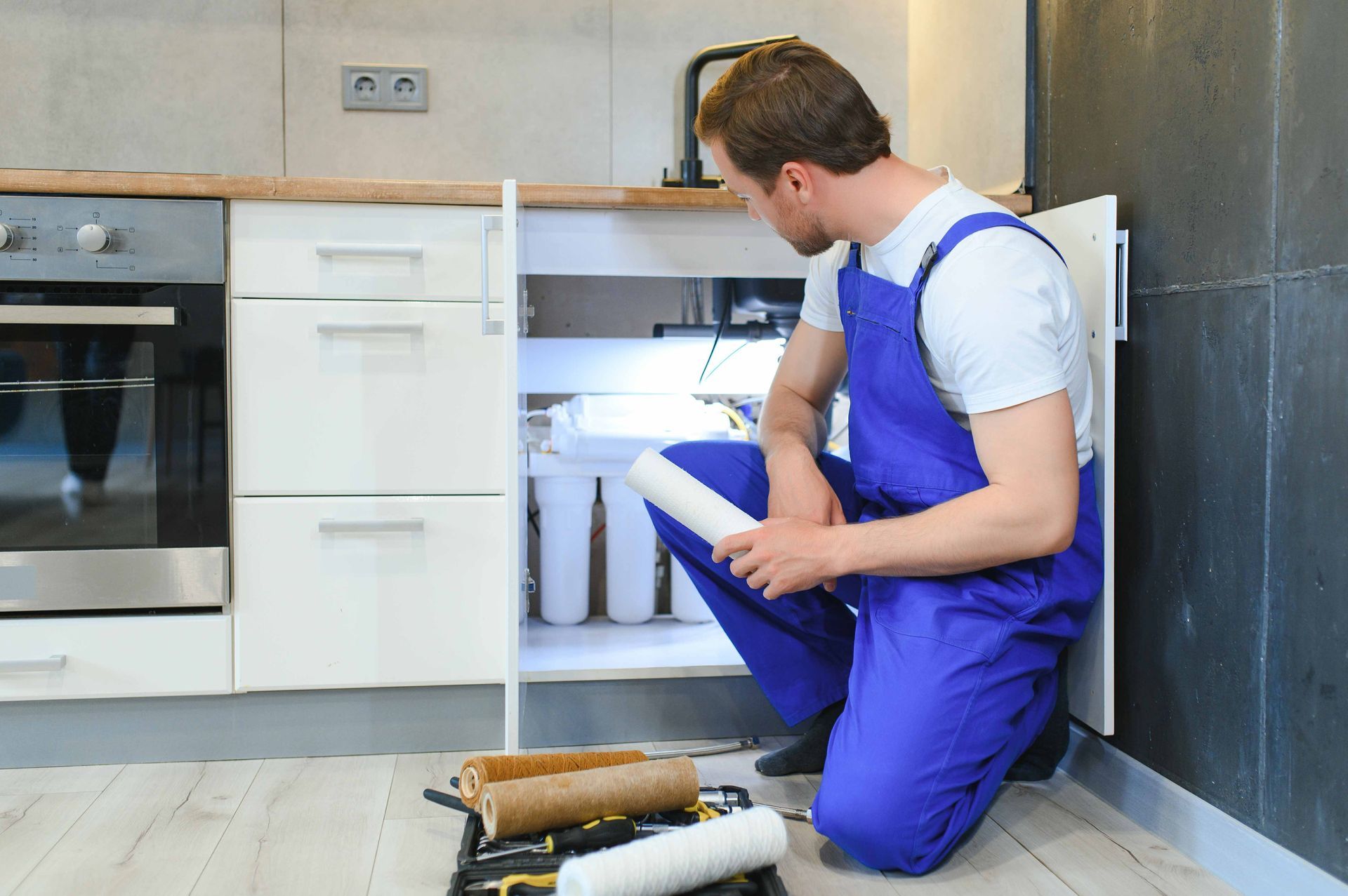A technician at a kitchen counter holding a replacement water filter